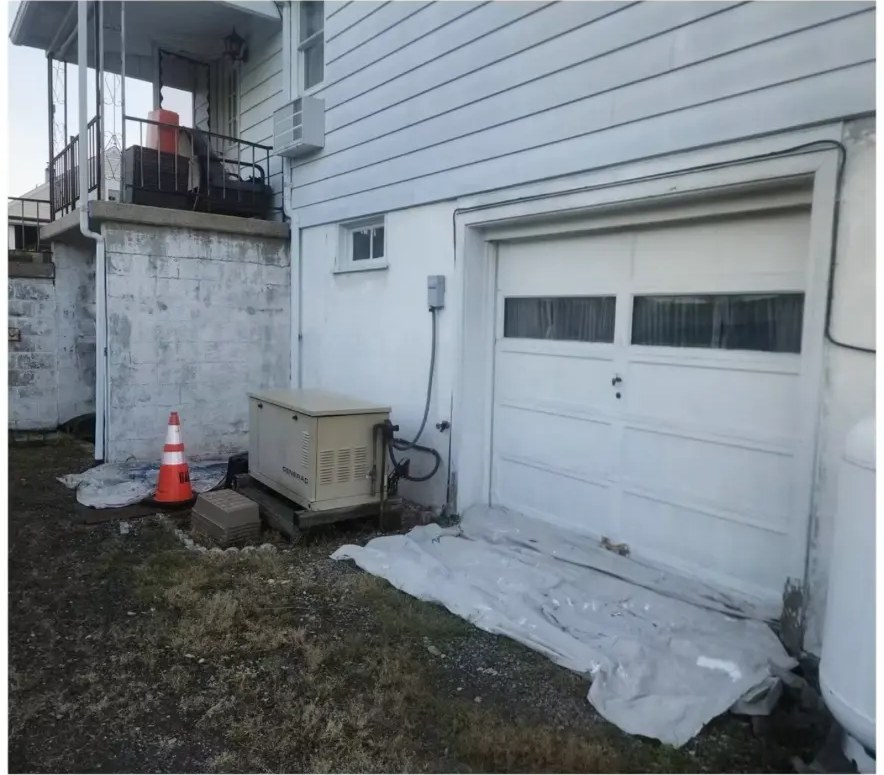 Before exterior painting: dingy grayish-white block and siding near a garage and generator