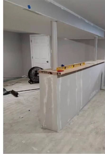 Before interior painting: bare, taped drywall on a basement bar half-wall