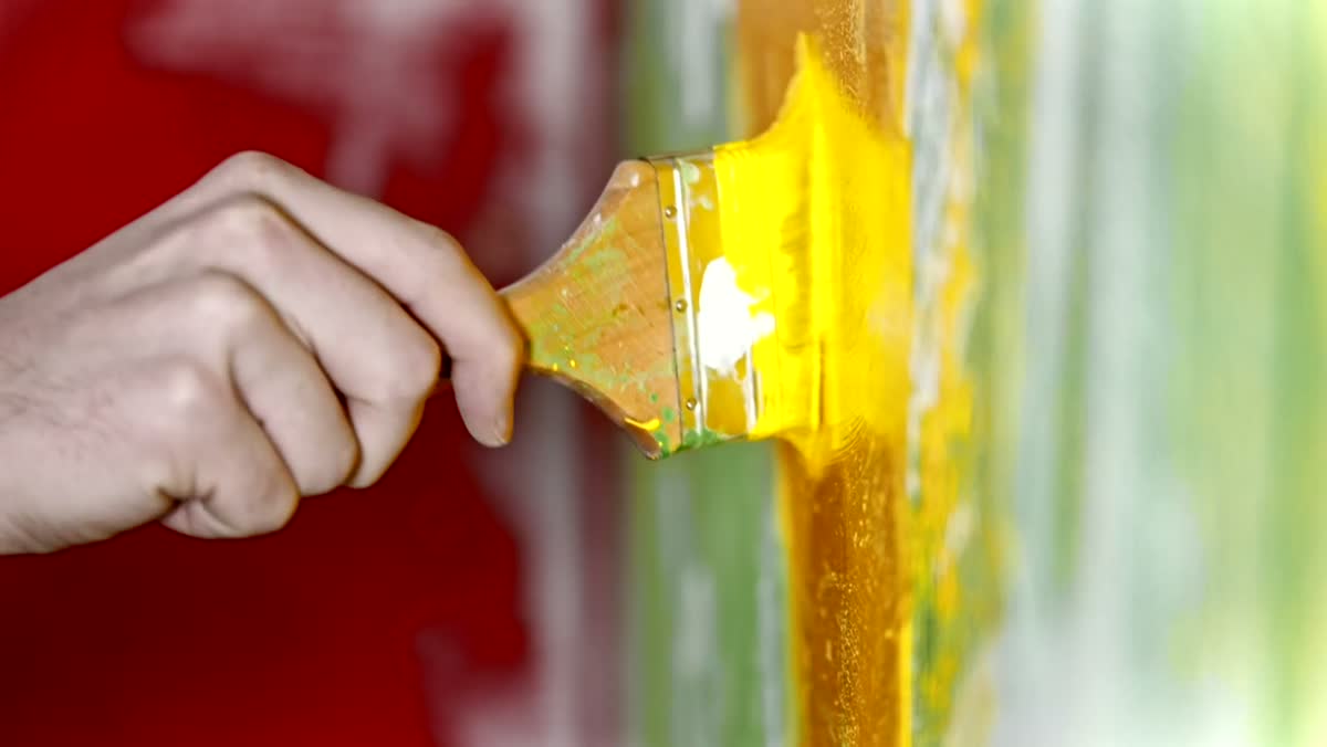 Painter brushing fresh paint along a wall